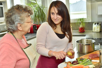 caregiver preparing meal for the elderly woman